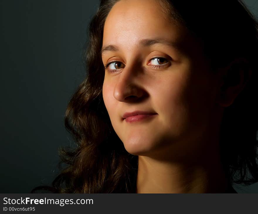 Low-key portrait about a smiling pretty girl with brown hair. Low-key portrait about a smiling pretty girl with brown hair