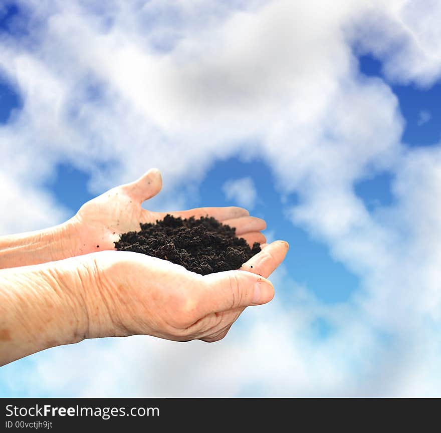 Soil in hands, sky wiht clouds