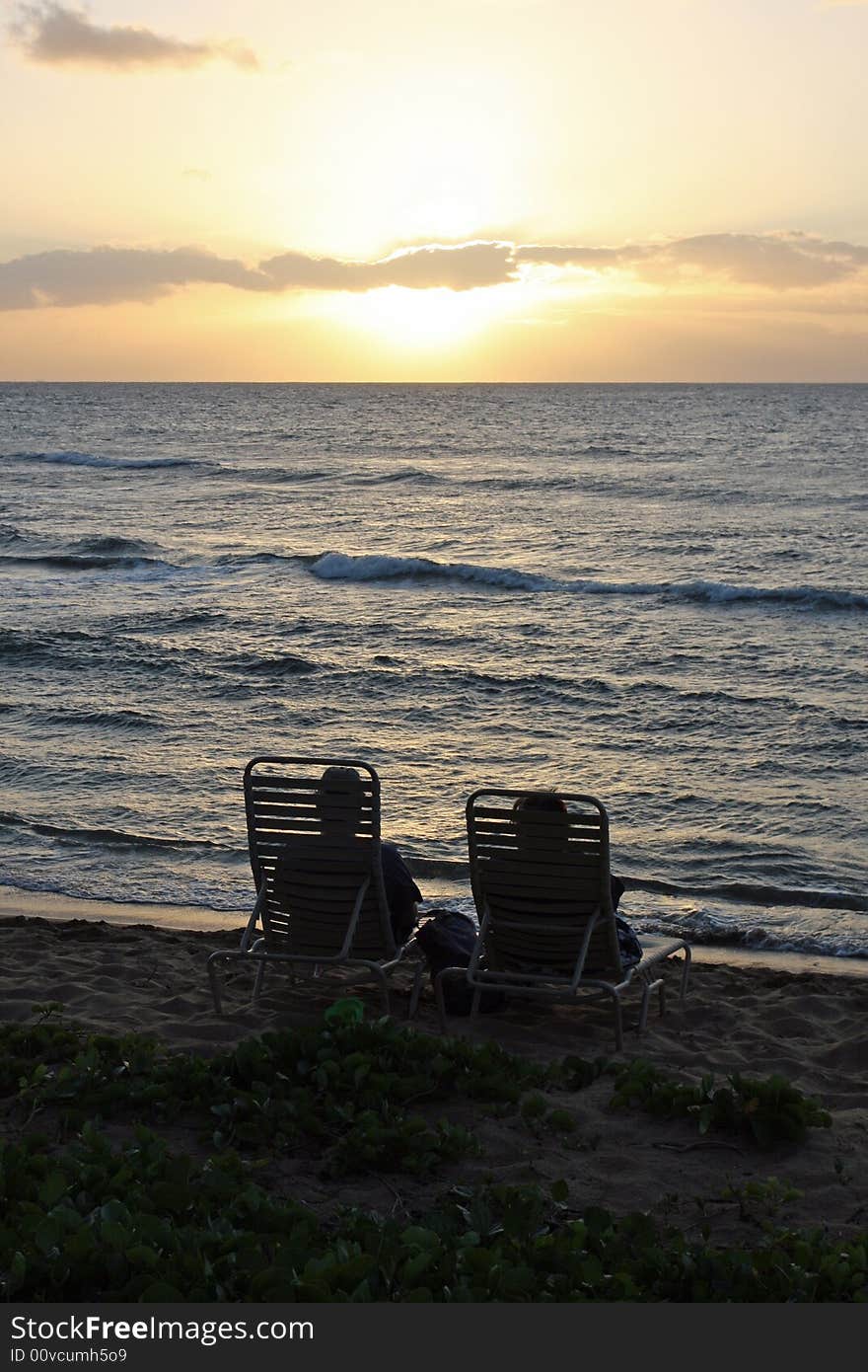 A couple watching the sun set over the Pacific ocean in Maui. A couple watching the sun set over the Pacific ocean in Maui.