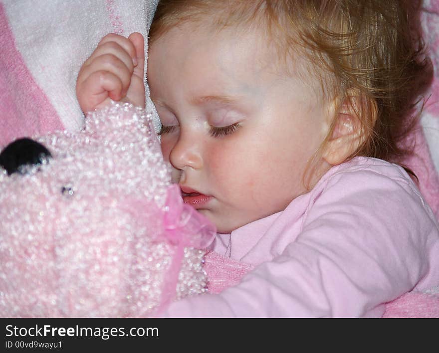 The beautiful girl in a pink T-short sleeps with her toy. The beautiful girl in a pink T-short sleeps with her toy