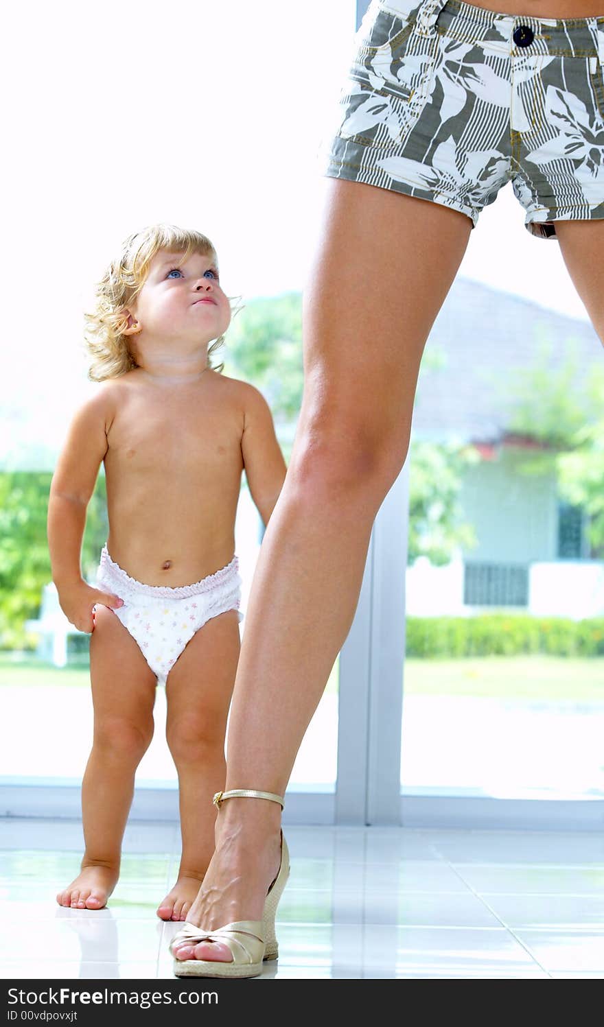 High key portrait of nice baby staying by  mama’s leg. High key portrait of nice baby staying by  mama’s leg