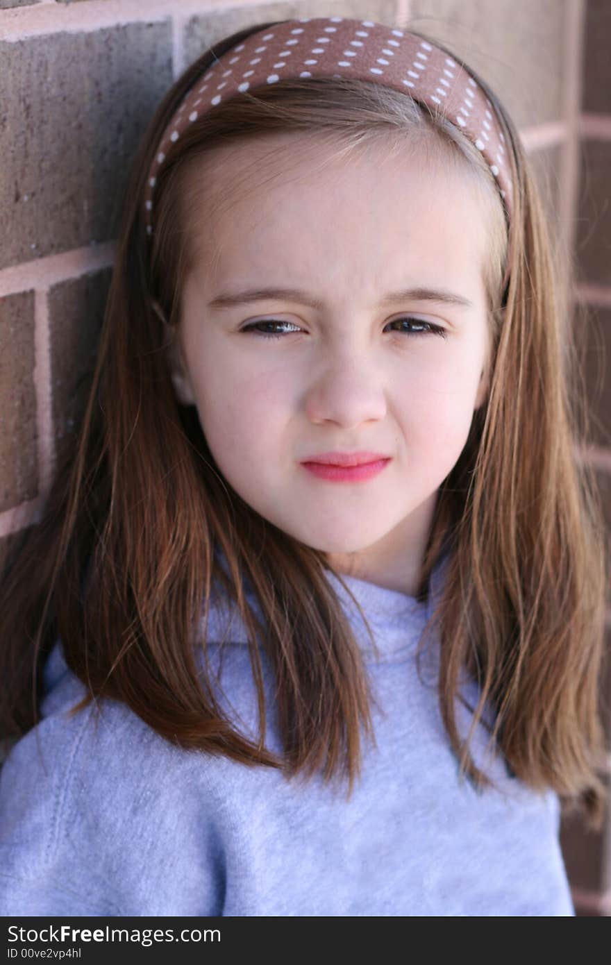 Beautiful eight year old child standing against a wall. Beautiful eight year old child standing against a wall