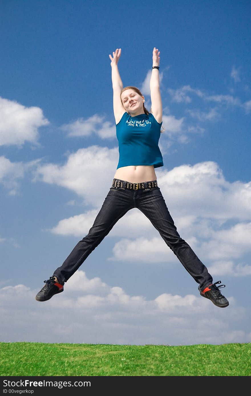 The happy jumping girl on a background of the blue sky