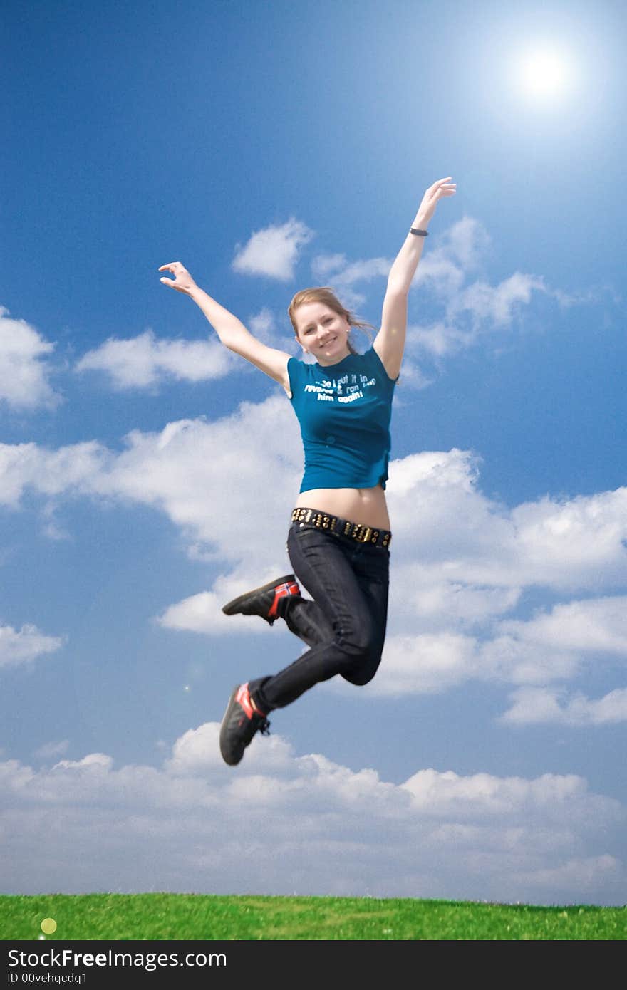 The happy jumping girl on a background of the blue sky