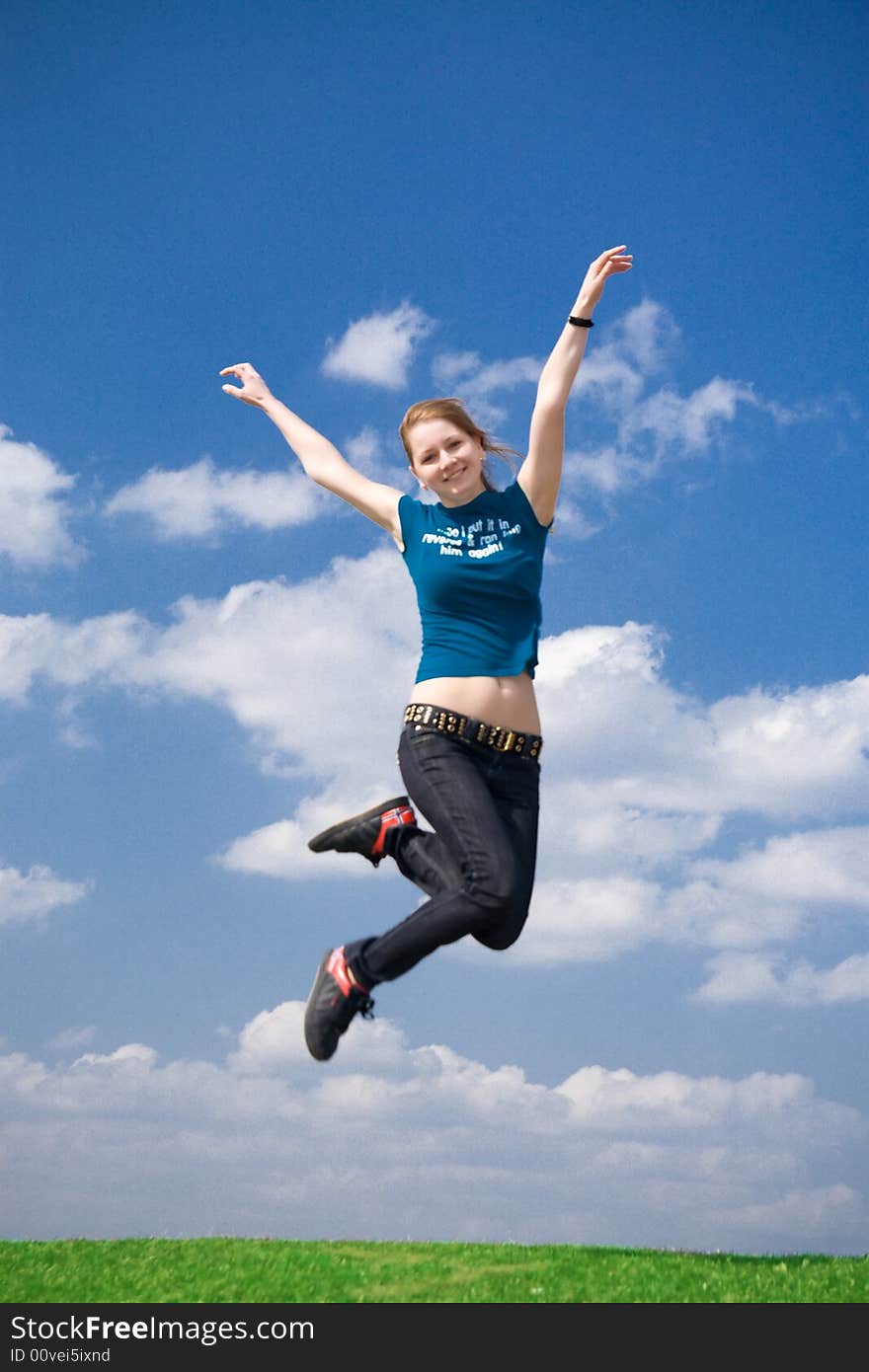 The happy jumping girl on a background of the blue sky