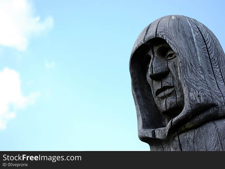 The head of a carved statue of a monk against the blue sky. The head of a carved statue of a monk against the blue sky