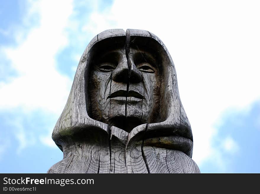 The head of a carved statue of a monk against the blue sky. The head of a carved statue of a monk against the blue sky