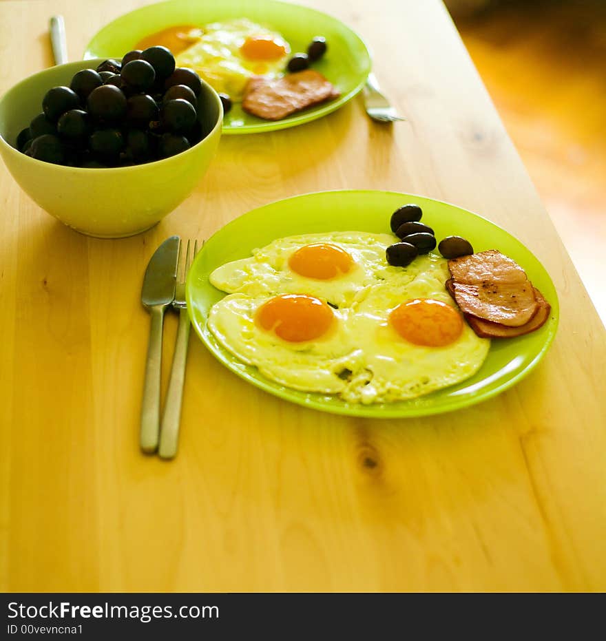 Breakfast food with eggs, bacon, grapes and olives