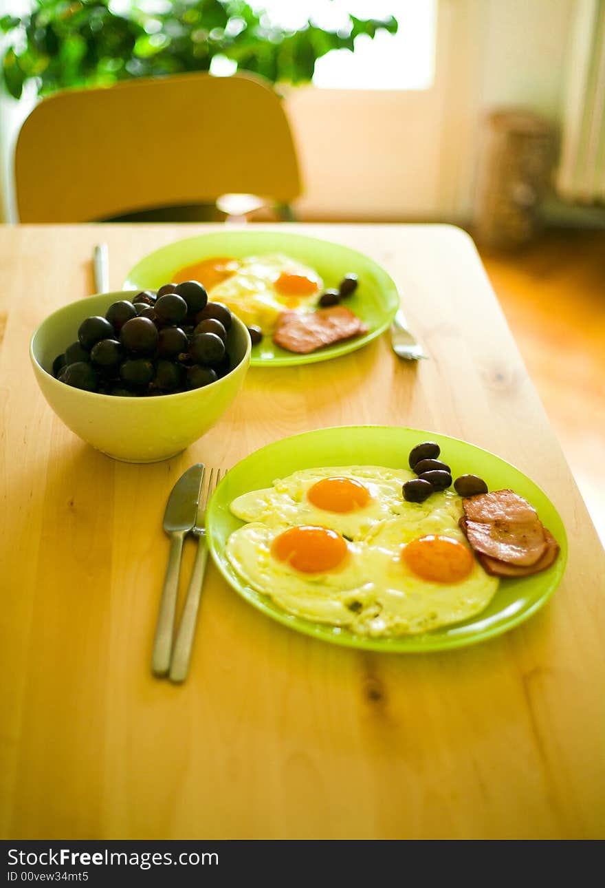 Breakfast food with eggs, bacon, grapes and olives