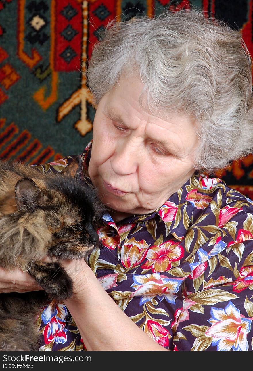 Grandmother with cat on her hands at home