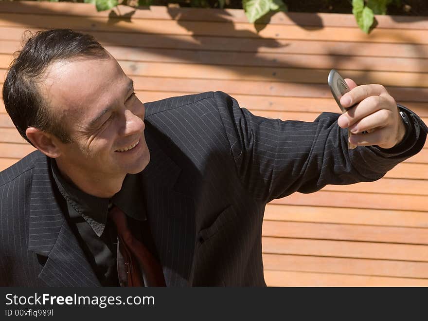 A businessman in a black pinstripe suit checking his cellphone's caller id. A businessman in a black pinstripe suit checking his cellphone's caller id.