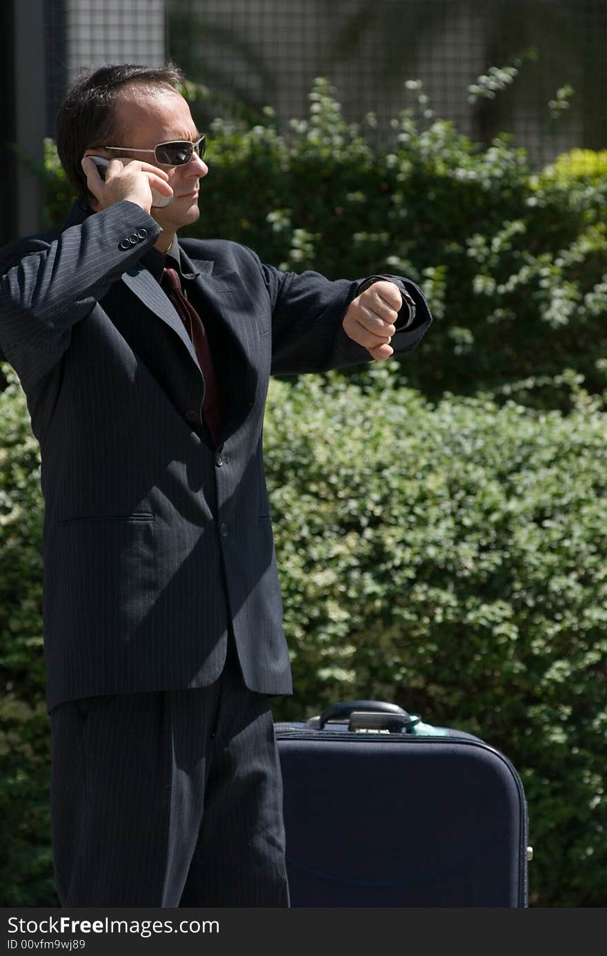 Latin american business executive checking his watch while on his cell phone. Latin american business executive checking his watch while on his cell phone