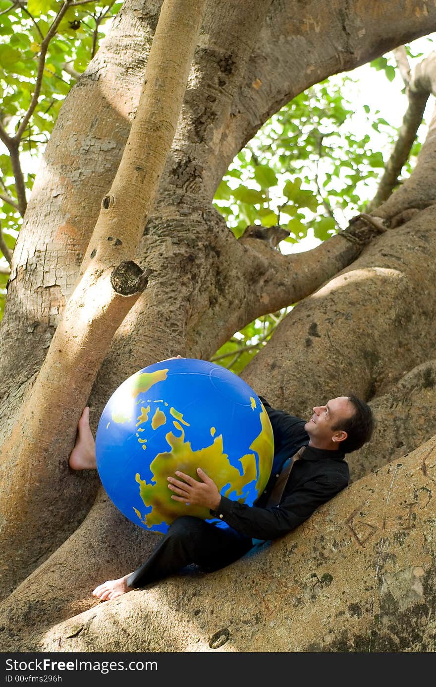 Latin american businessman working on a laptop while sitting outdoors in a tree. Vertically framed shot. Latin american businessman working on a laptop while sitting outdoors in a tree. Vertically framed shot