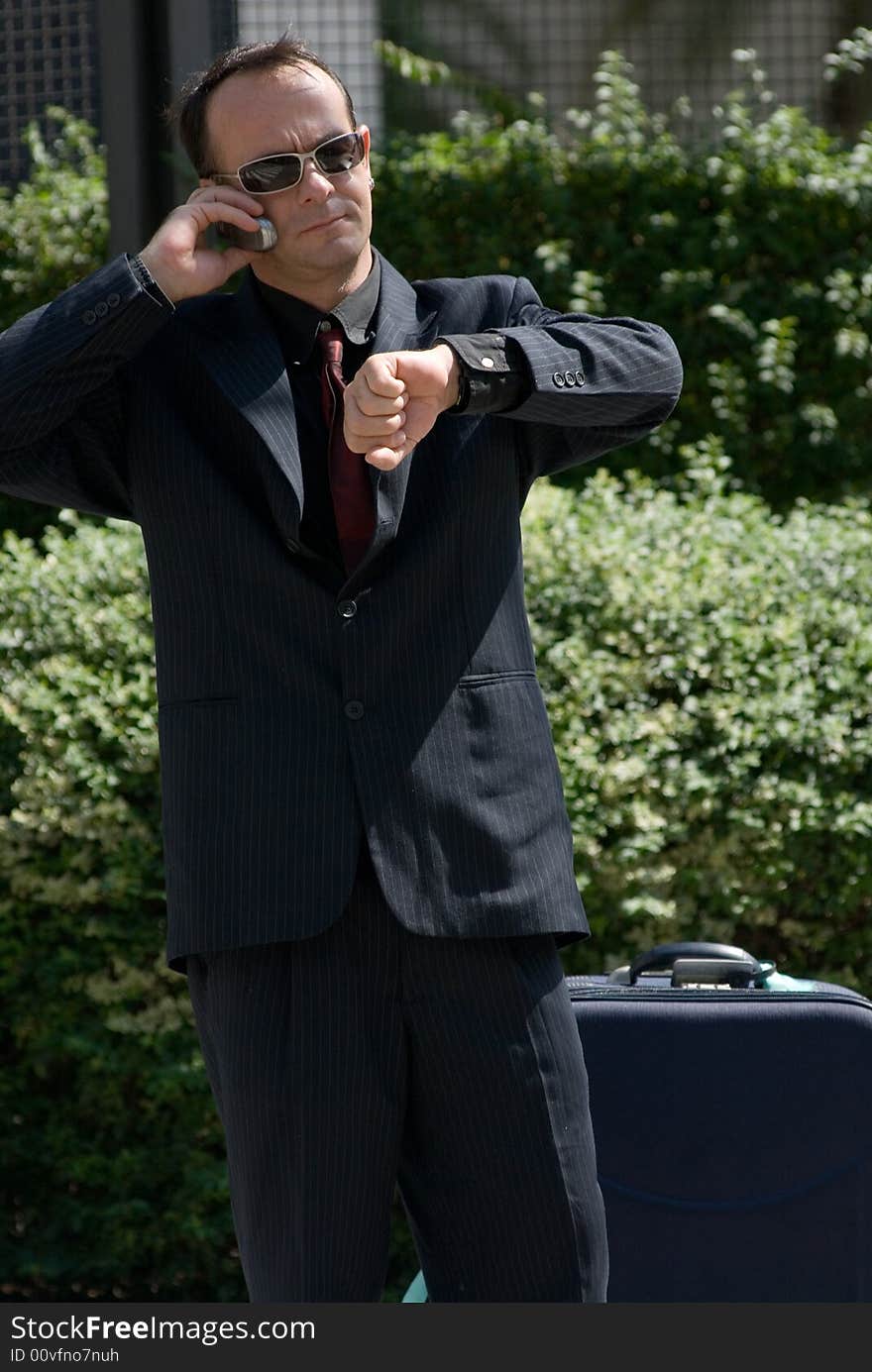 Latin american businessman checking his watch while on his cell phone. Latin american businessman checking his watch while on his cell phone