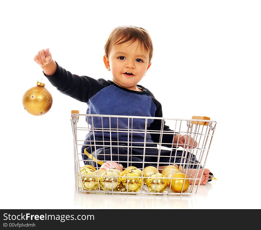 Happy baby boy playing in a wire basket of gold colored Christmas bulbs.  Isolated on white. Happy baby boy playing in a wire basket of gold colored Christmas bulbs.  Isolated on white.