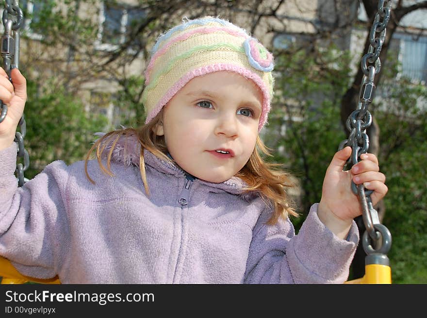 Little sweet girl is swinging on a playground. Little sweet girl is swinging on a playground