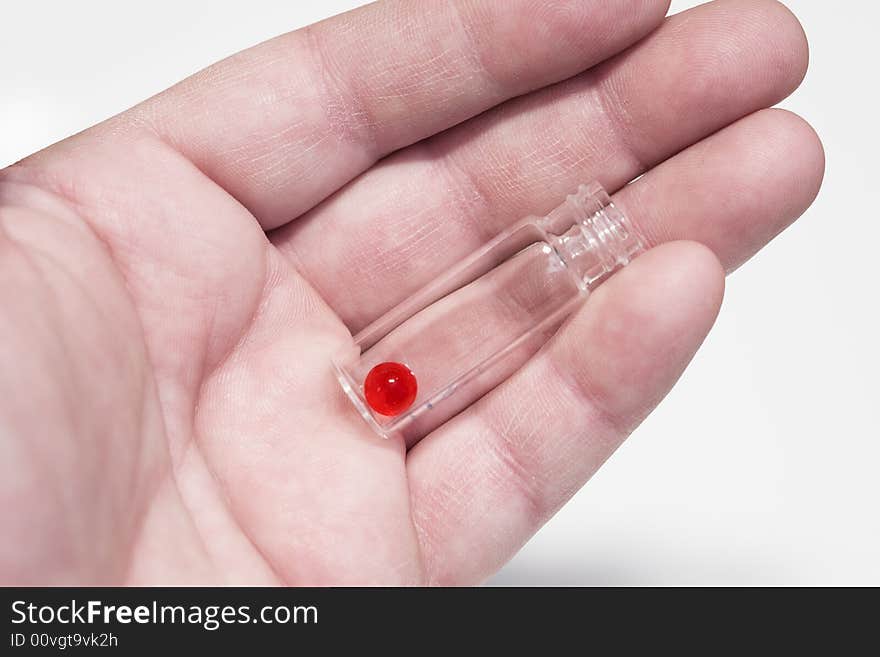 The hand holds the vial with a red pill. Close-up, shallow depth of field. The hand holds the vial with a red pill. Close-up, shallow depth of field.