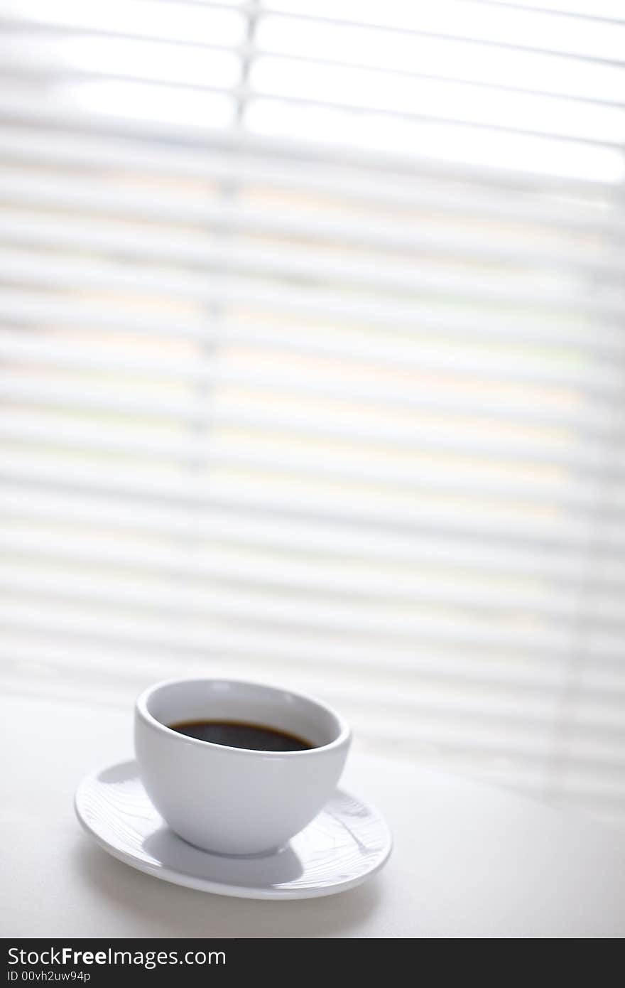 White cup on the table in front of window / copyspace