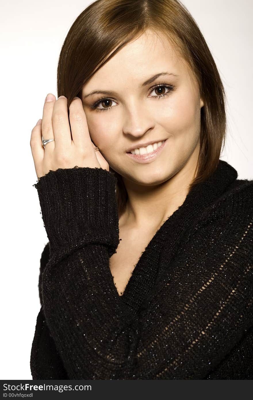 Beautiful brunette wearing black sweater on light background. Beautiful brunette wearing black sweater on light background