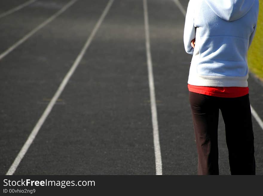 Lanes of a race track with woman standing and looking down the track. Lanes of a race track with woman standing and looking down the track