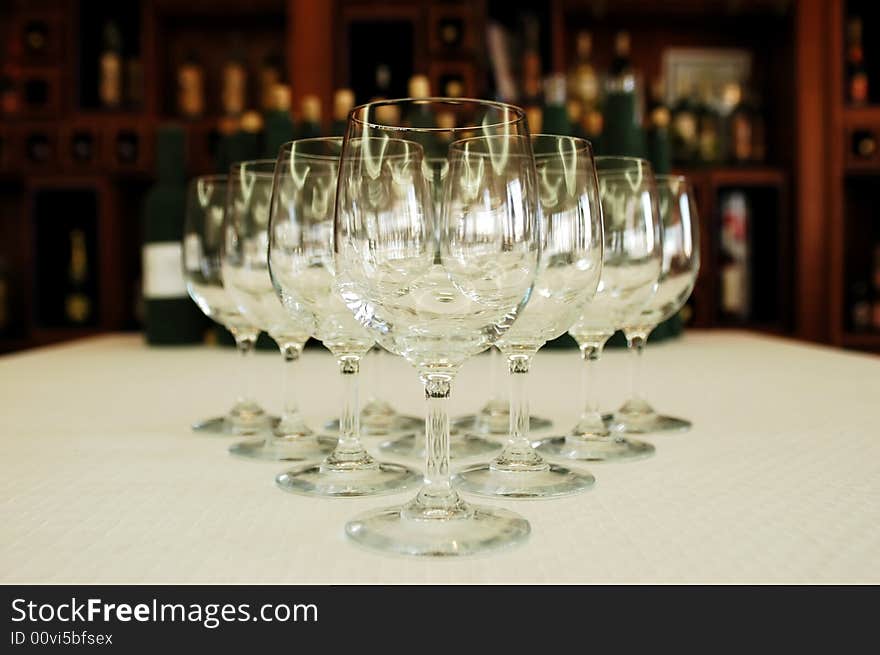 Wine glasses in a row, wine bottles on background, focus on glass. Wine glasses in a row, wine bottles on background, focus on glass