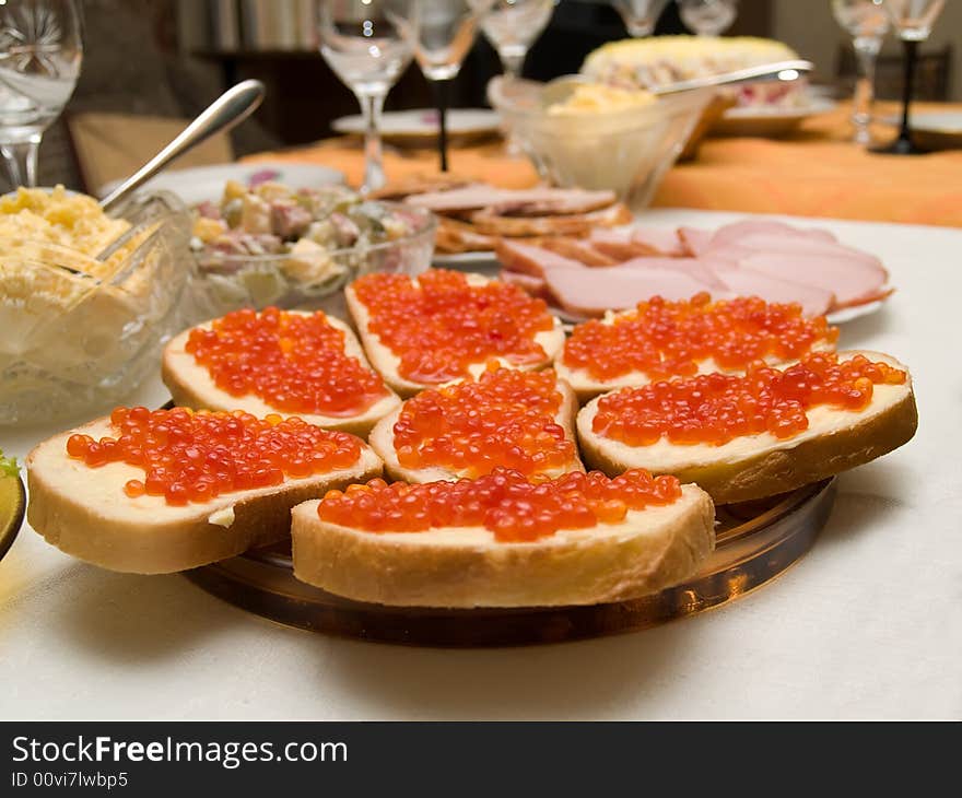 Table covered for a celebratory dinner. Sandwiches with red caviar.