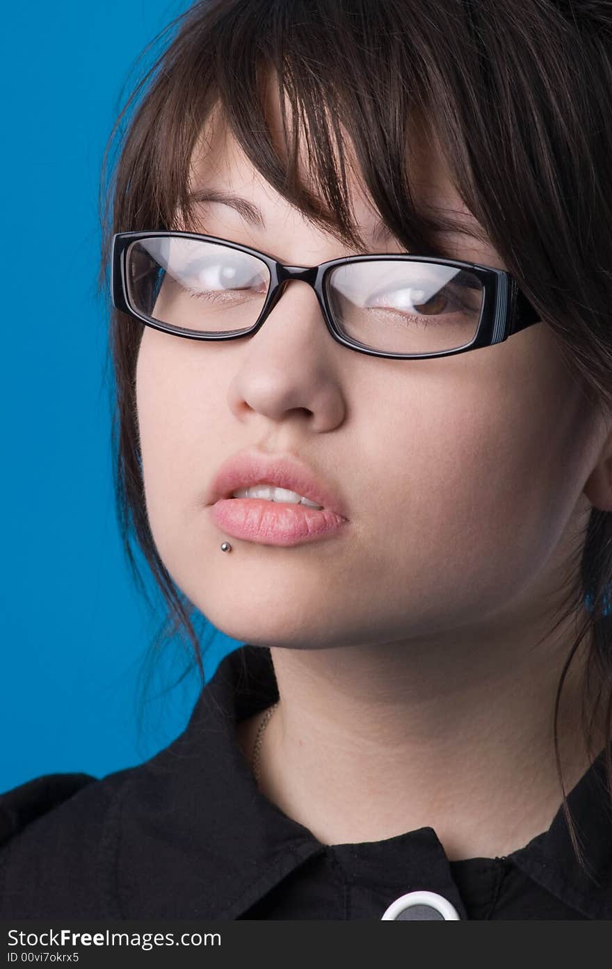 The girl on a dark blue background tries on glasses. The girl on a dark blue background tries on glasses.