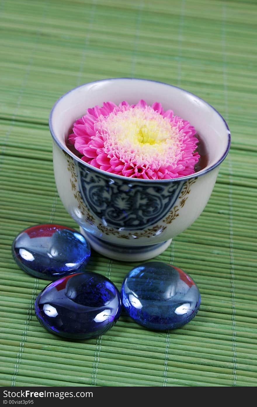 Pink flower in a vase with blue stones.