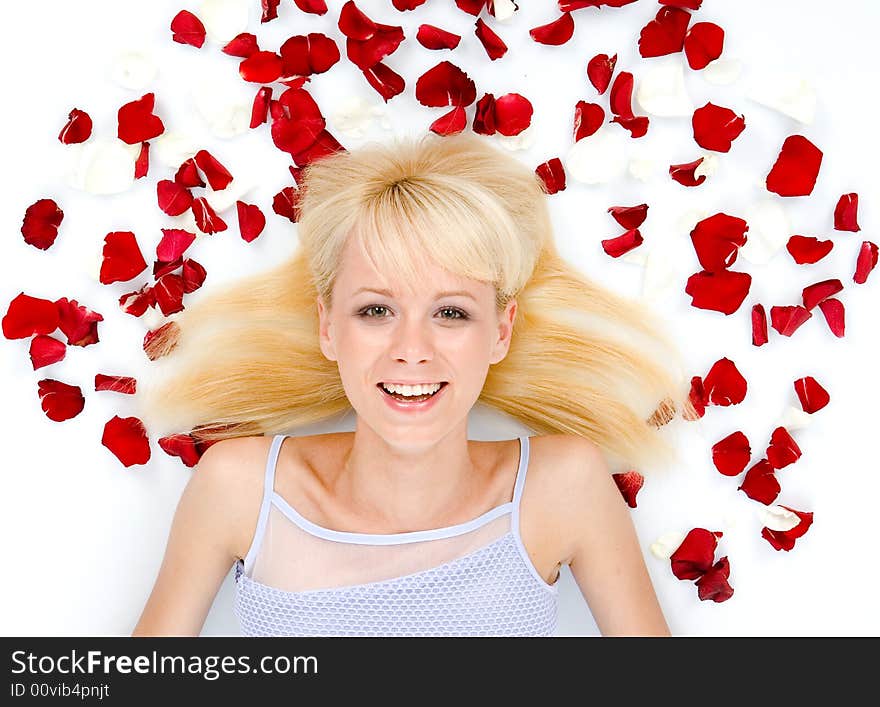 Beautiful young woman throwing rose petals against a white background