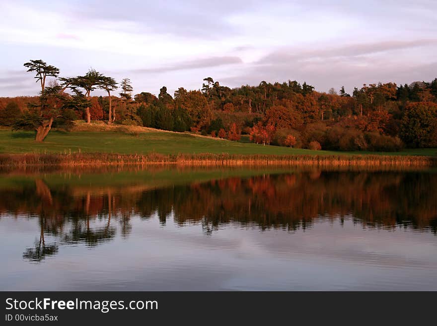 Tree line reflected into lake as the sun sets