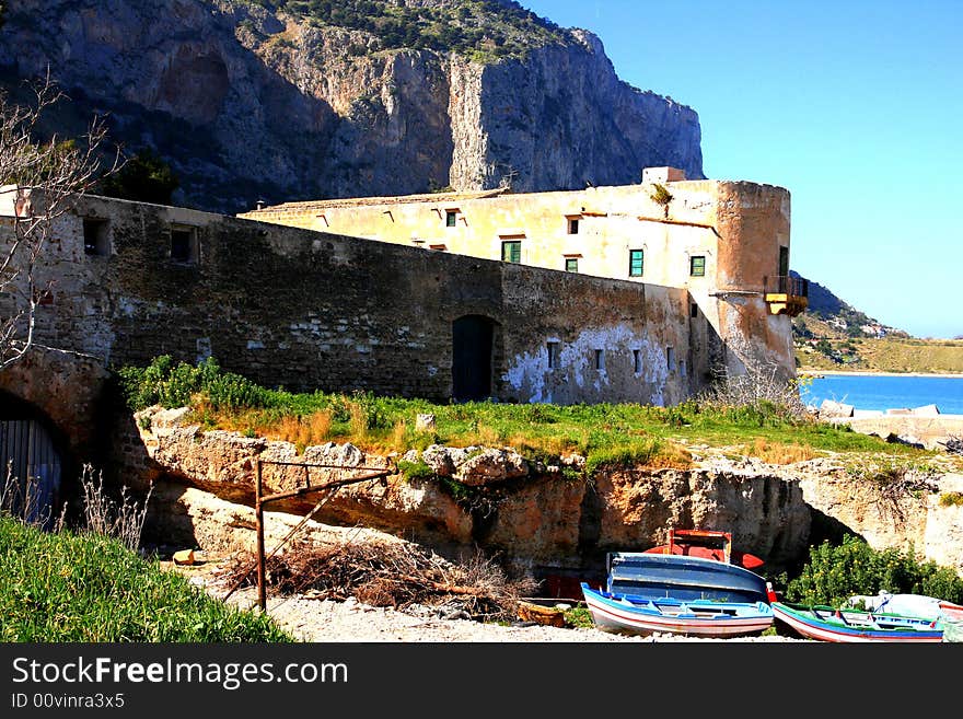 Ancient Tuna fishing construction Tonnara Bordonaro XVI century in Palermo. View on Mount Pellegrino blue sky and sea. Island of Sicily, Italy. Ancient Tuna fishing construction Tonnara Bordonaro XVI century in Palermo. View on Mount Pellegrino blue sky and sea. Island of Sicily, Italy