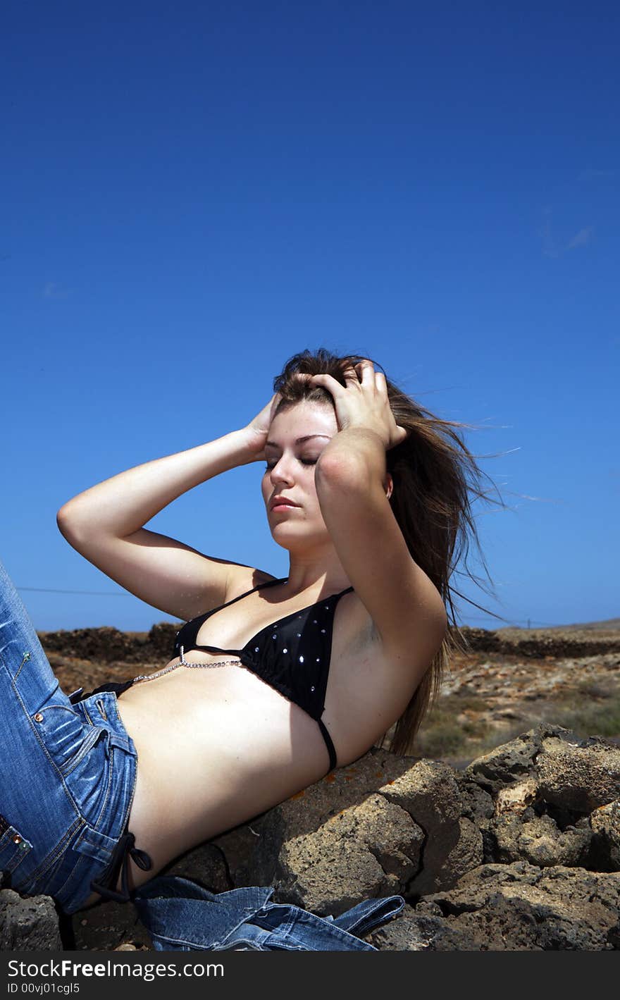 Sexy young woman with blue jeans over stones under blue sky. Sexy young woman with blue jeans over stones under blue sky