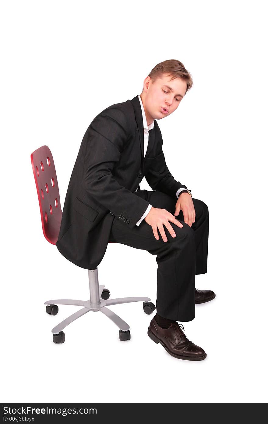 Young man in suit sits on chair on a white