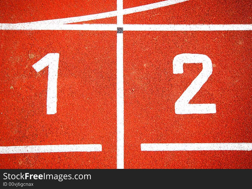 First two numbers of a racetrack, on red tarmac, for runners