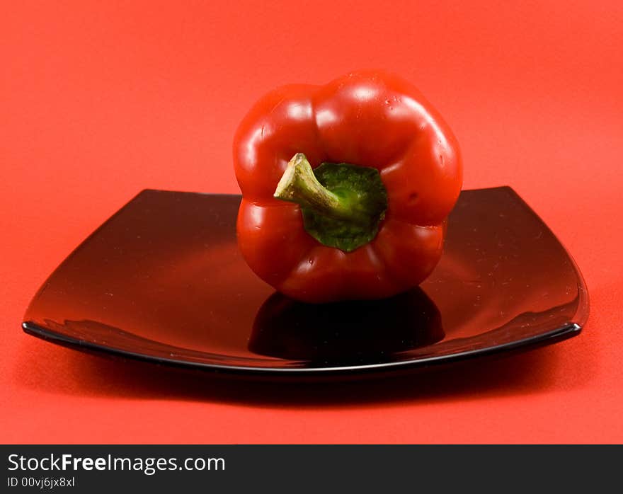 Red pepper on plate on red background