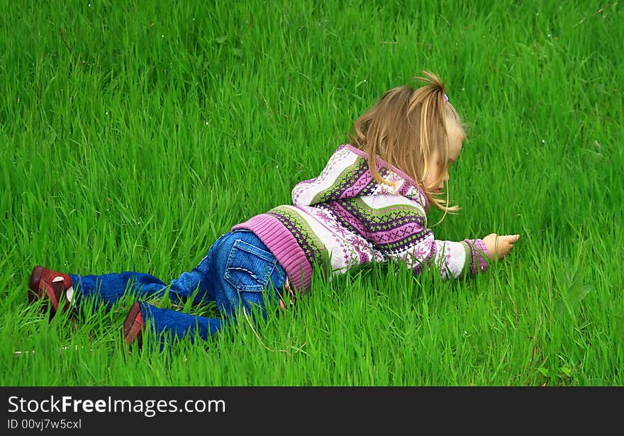 Little girl walks in the spring on a young grass