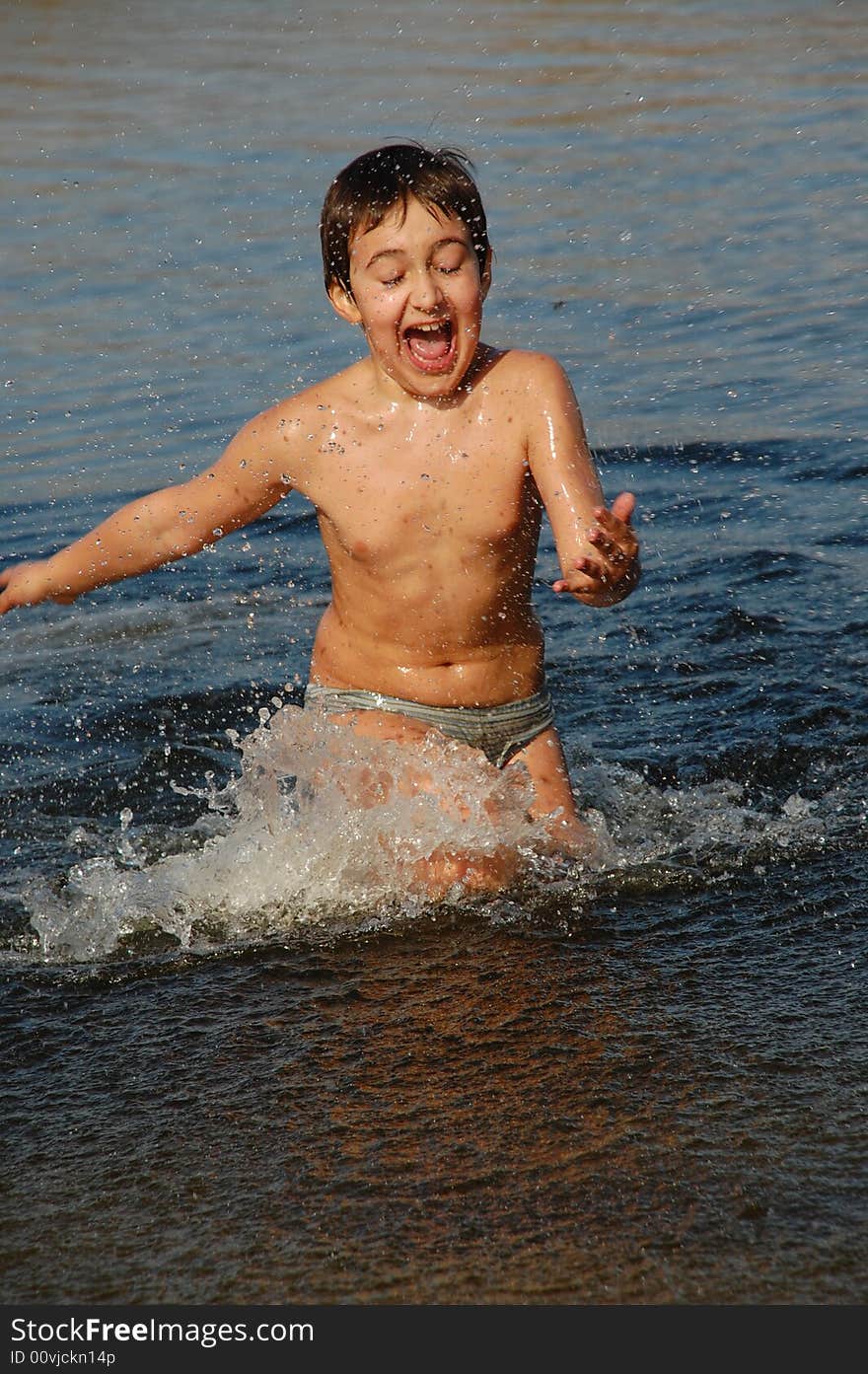 Boy running merrily in water having fun on the beach. Boy running merrily in water having fun on the beach