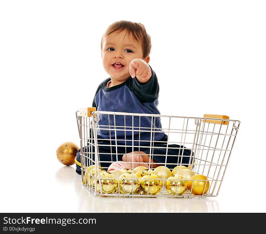 Happy baby boy pointing directly at the viewer from behind a wire basket of gold Christmas bulbs.  Isolated on white. Happy baby boy pointing directly at the viewer from behind a wire basket of gold Christmas bulbs.  Isolated on white.