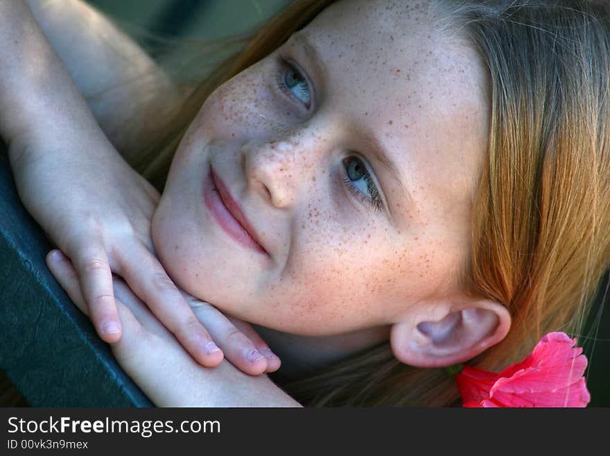 A white caucasian girl with a pink flower in her hair. A white caucasian girl with a pink flower in her hair