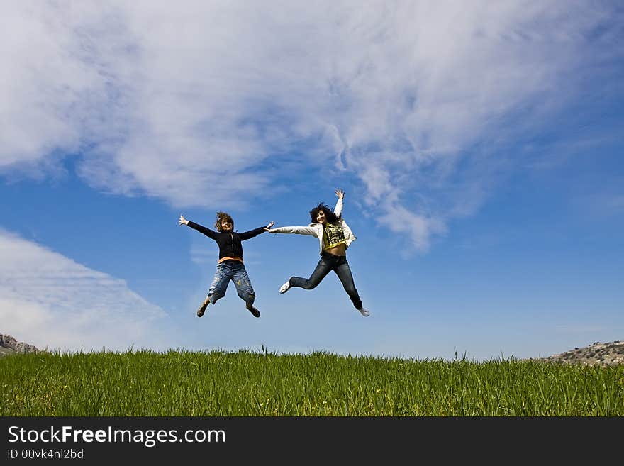 Young friends jumping on green meadow