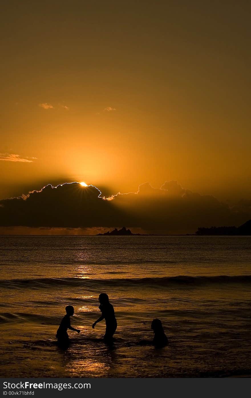 A morning sun coming up in the bay of Baler Aurora with three kids enjoying the water.