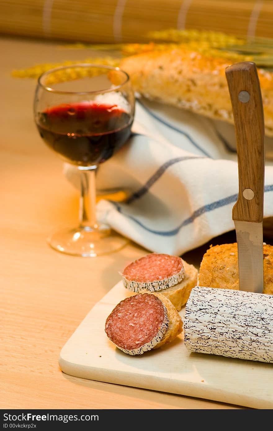 Still life with red wine,sausage and bread roll