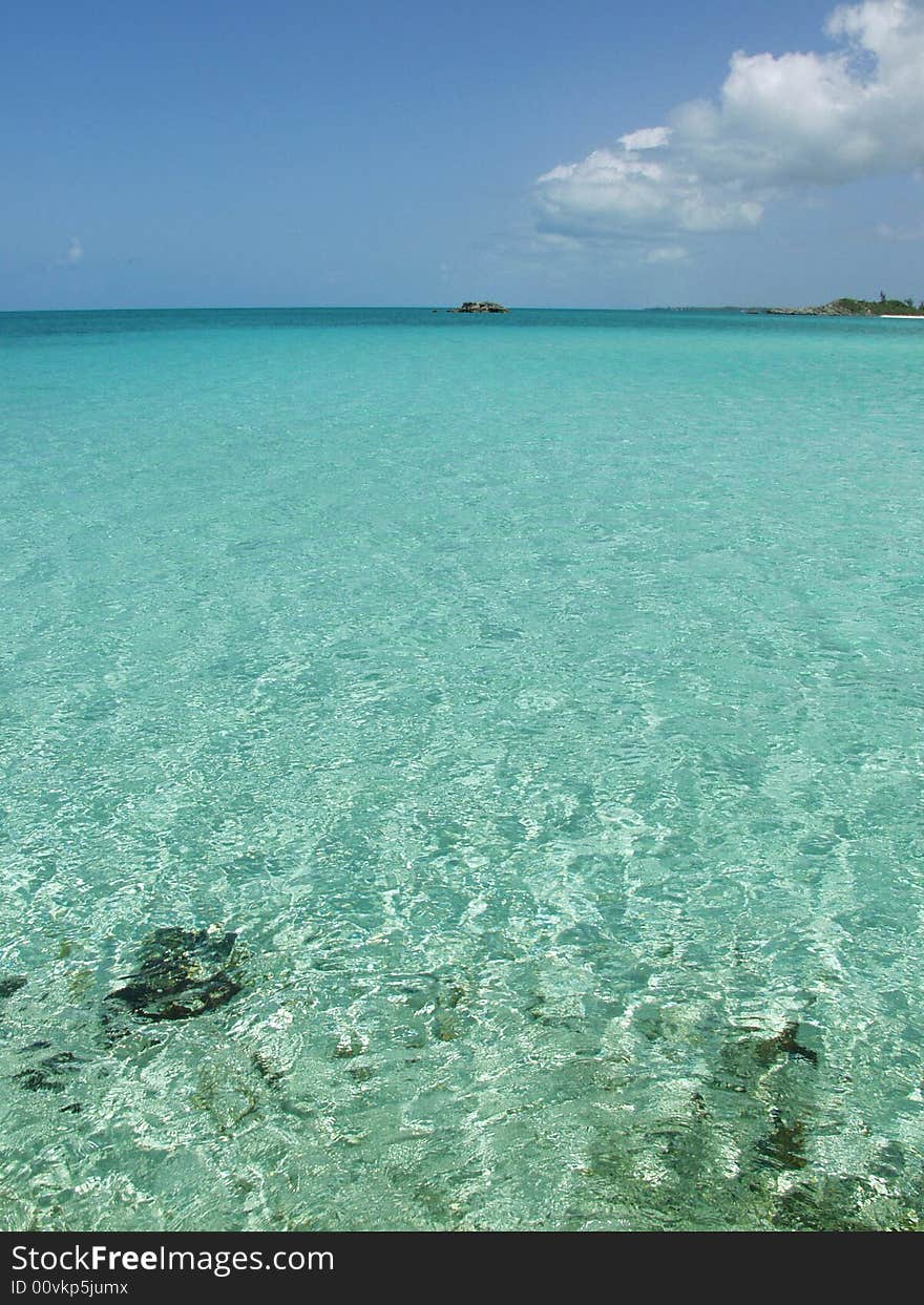 Caribbean bay with clear water, blue sky clouds and island.