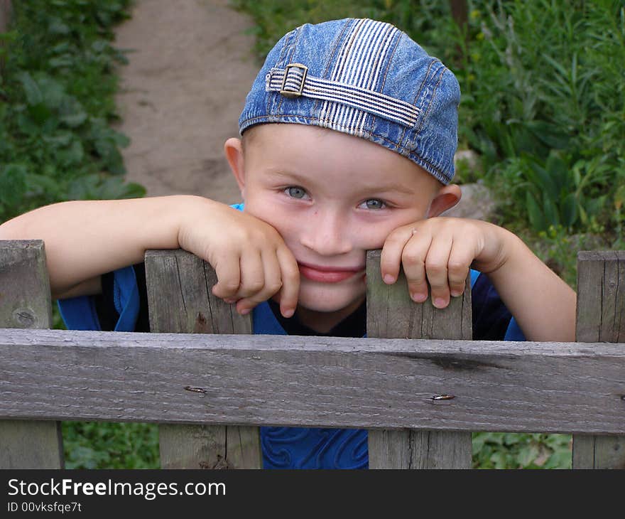 Little Boy Leaned Against The Fence