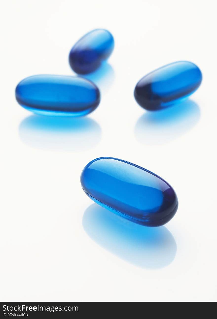 Blue capsules on white background, vertical image