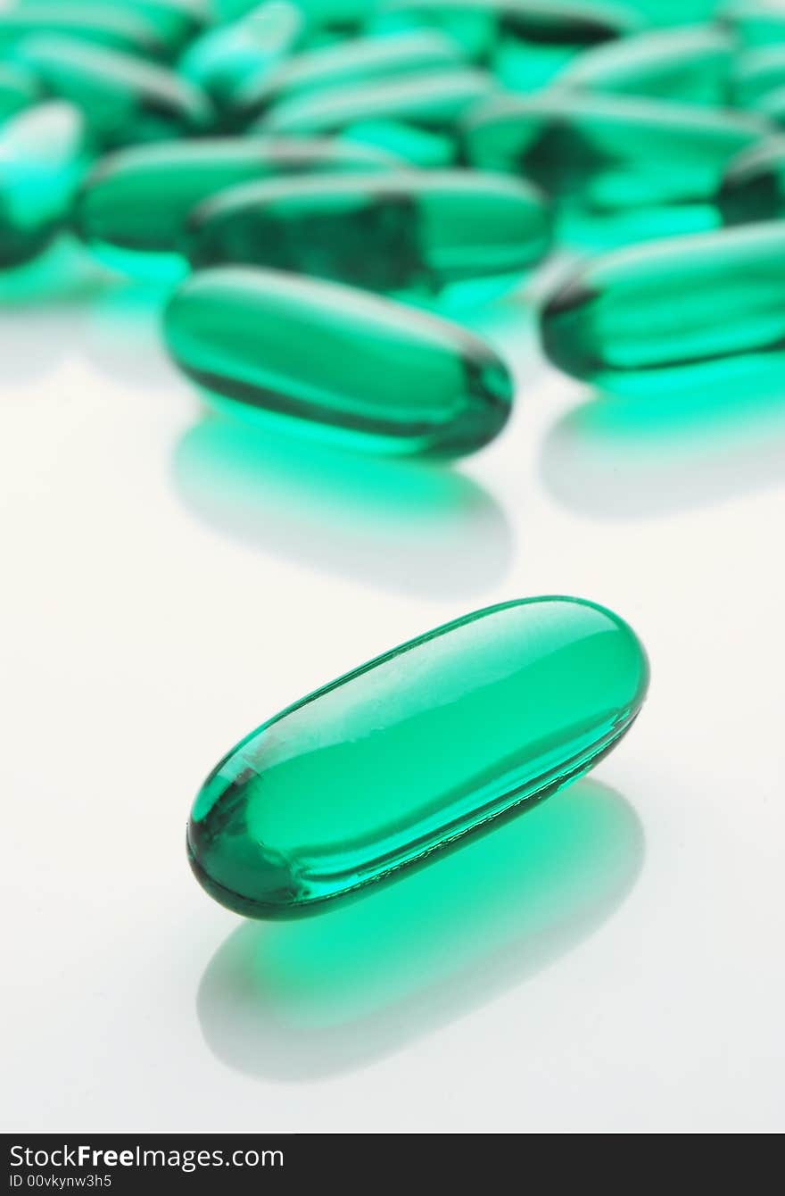 Green capsules on white background, vertical image