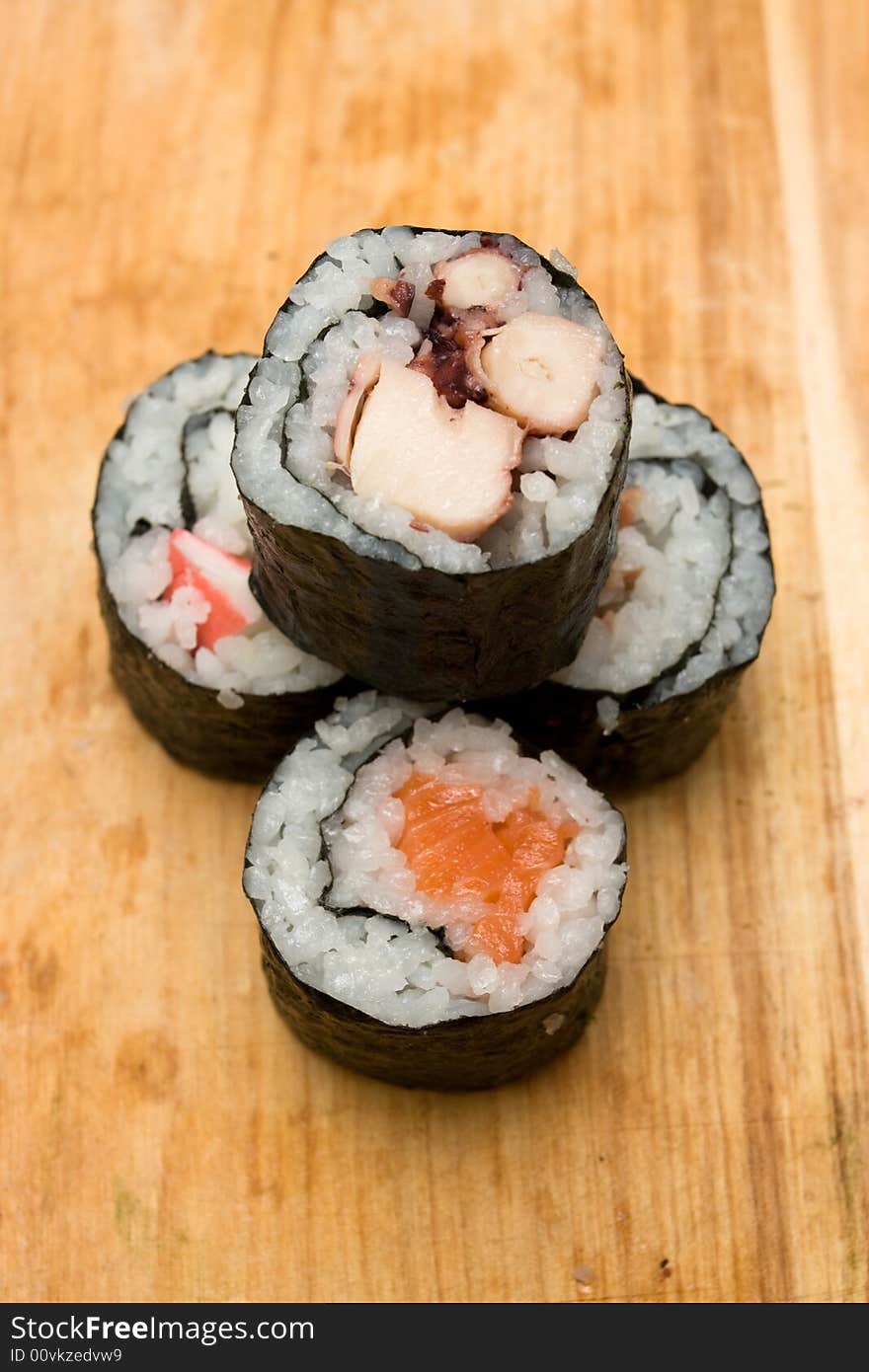 Four different sushi rolls on cutting board.