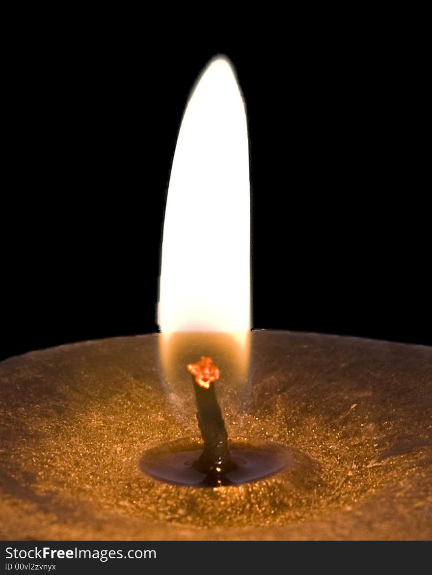 A close up of a burning candle over a black background. A close up of a burning candle over a black background.