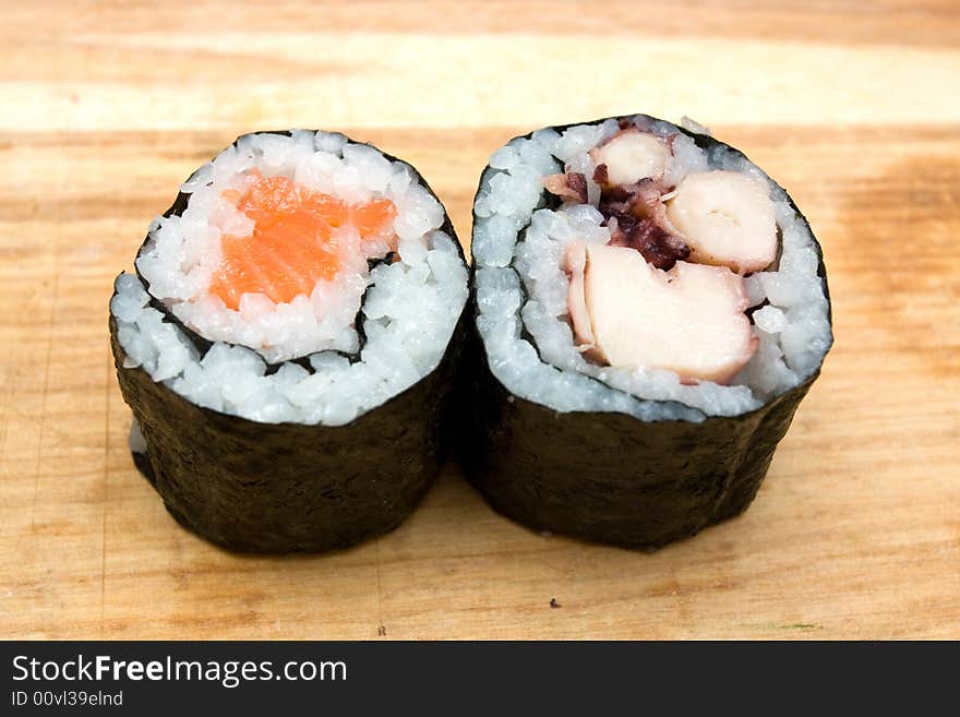 Pair of sushi rolls on cutting board.