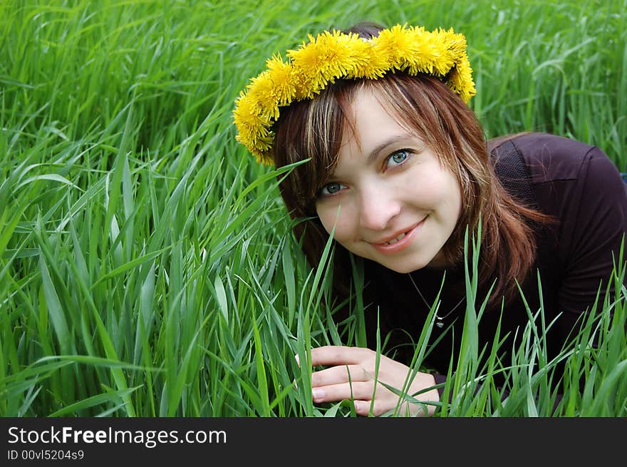 Girl with dandelion diadem in hair over green grass. Girl with dandelion diadem in hair over green grass